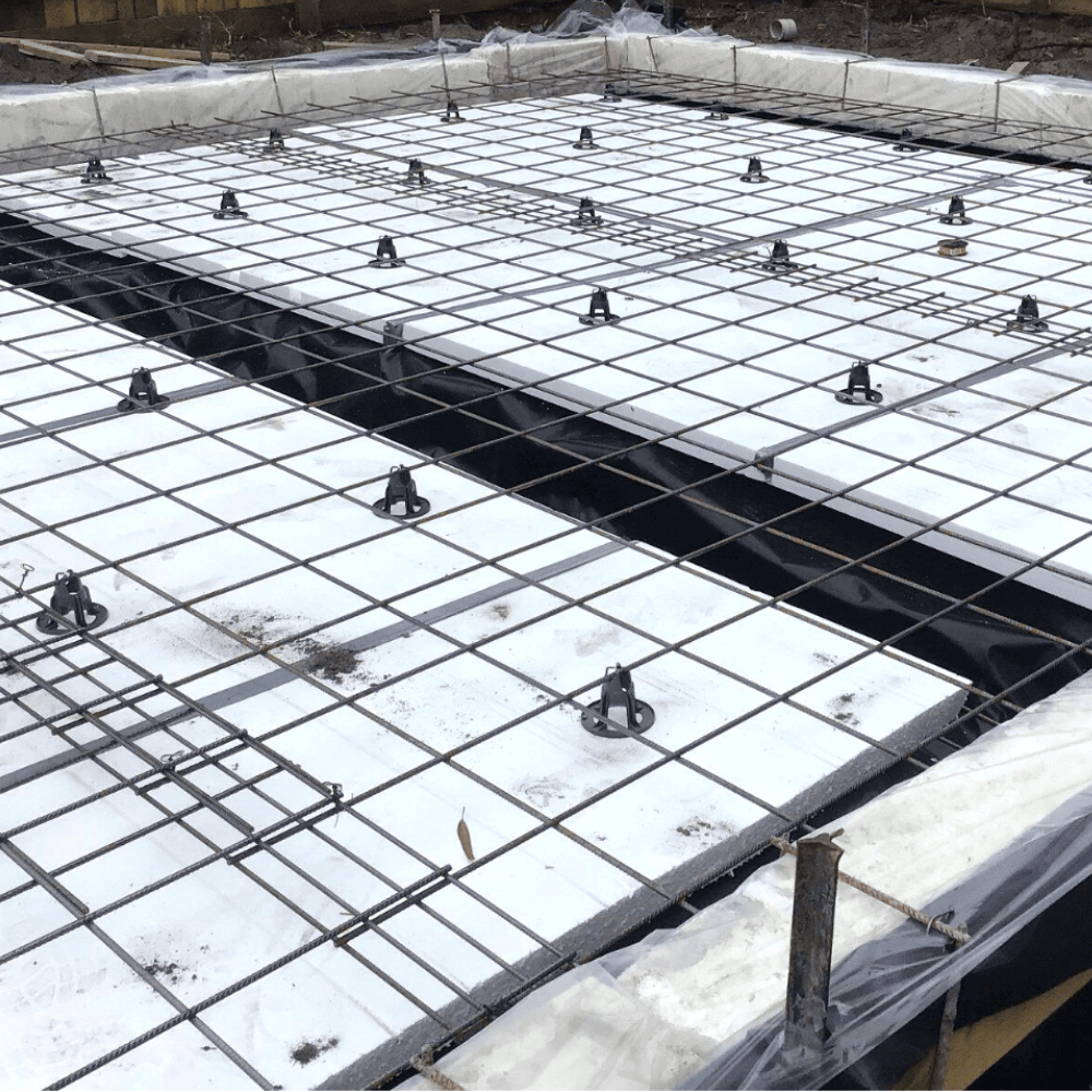 Concrete foundation with slabmate and steel reinforcement on a construction site.